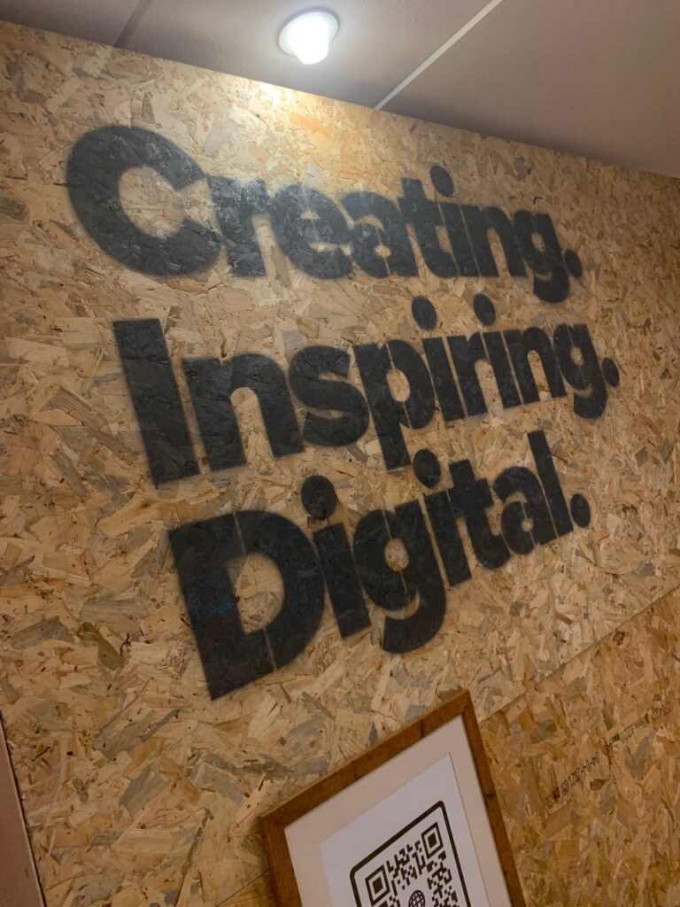 Eon Visual Media's mission of 'Creating. Inspiring. Digital' spray painted across a plain wooden background