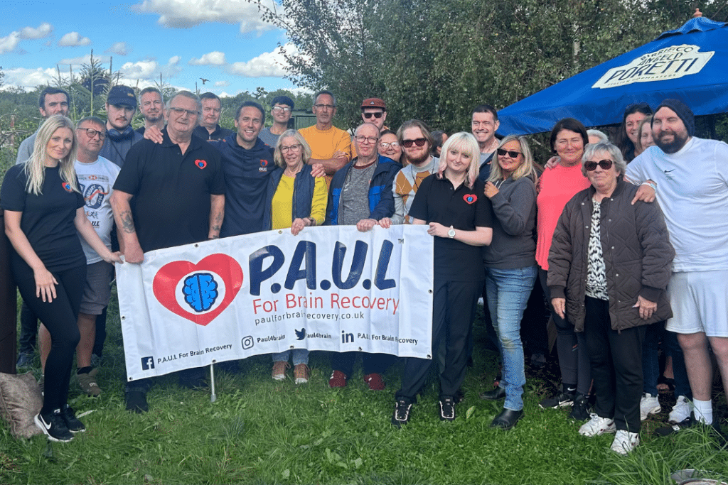 P.A.U.L For Brain Recovery logo held up by a group of service users