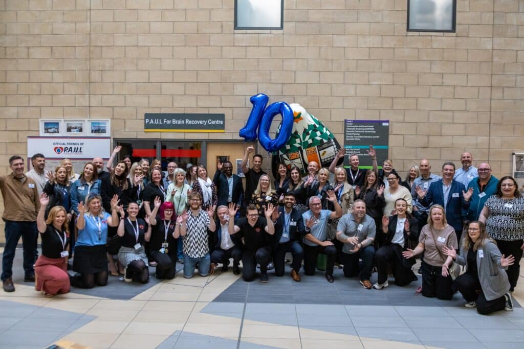 Business supporters gather for a photo near a blue number 10 balloon at P.A.U.L For Brain Recovery